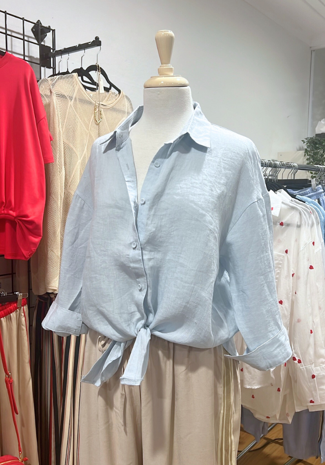 Light blue shirt on a mannequin with a clothing rack in the background