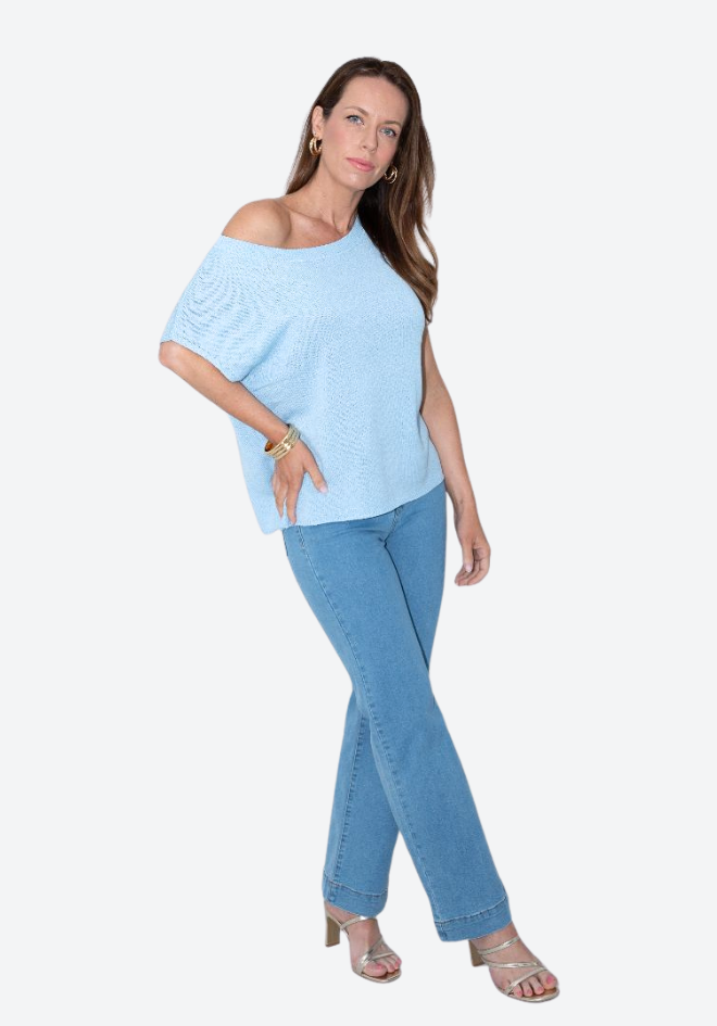 Woman wearing a light blue off-shoulder top and jeans on a white background