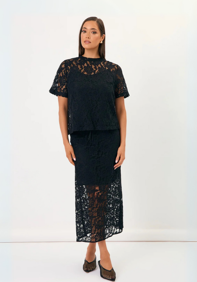 Woman wearing a black lace top and skirt set on a white background