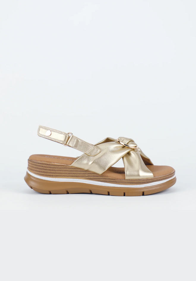 Gold sandal with a bow on a white background