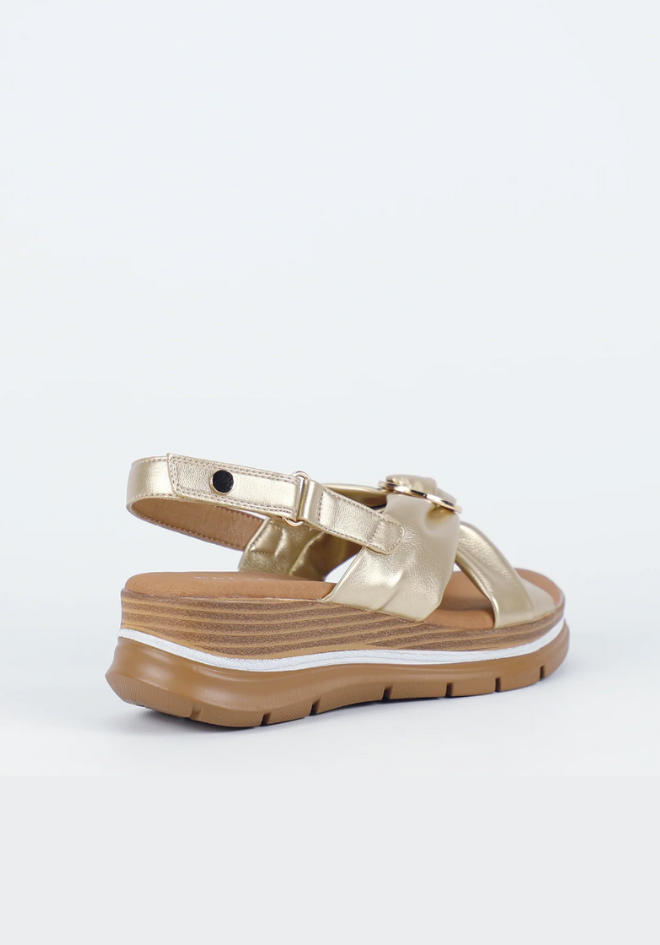 Gold sandal with a white sole on a light gray background