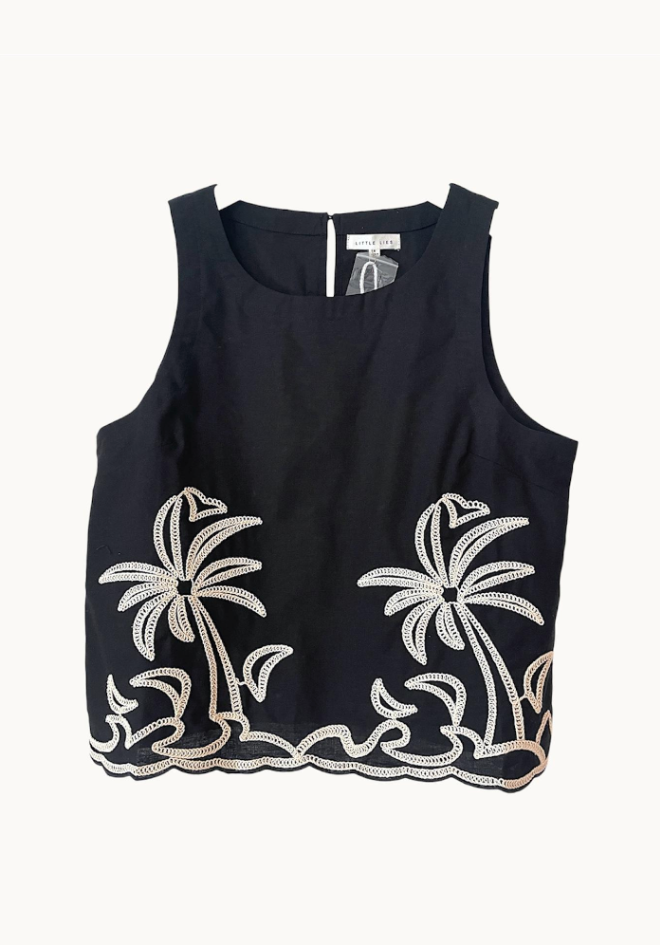 Black sleeveless top with white floral embroidery on a white background