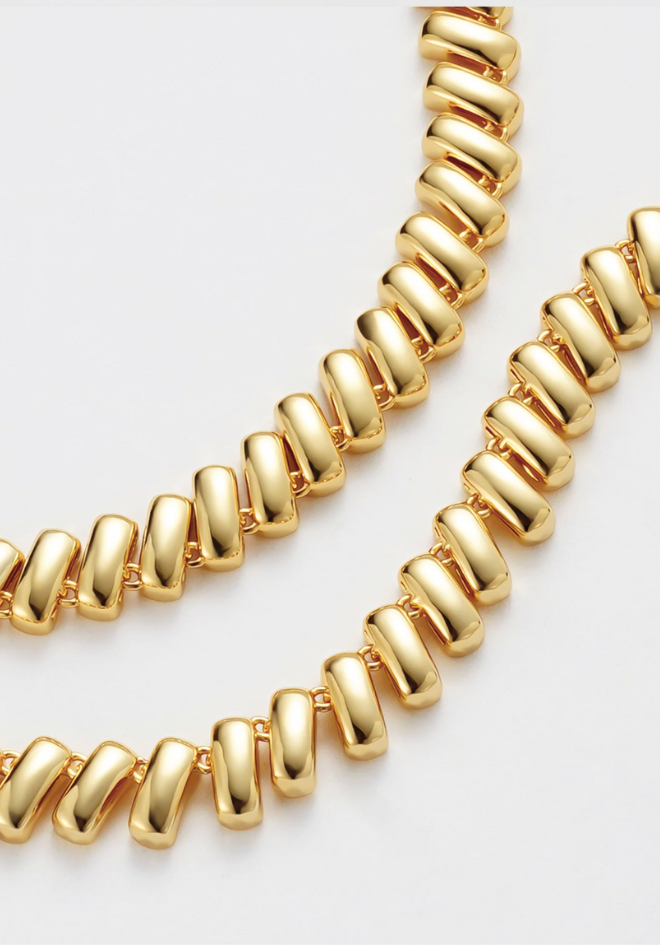 Gold necklace on a light gray background