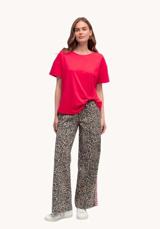Woman wearing a red top and patterned pants on a white background