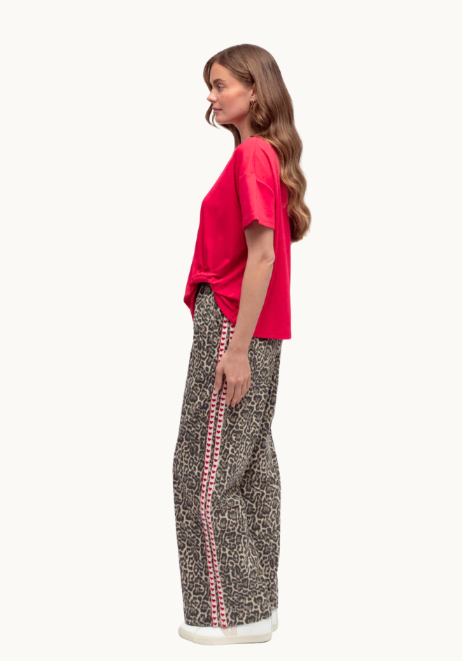 Woman wearing a red top and patterned pants on a white background