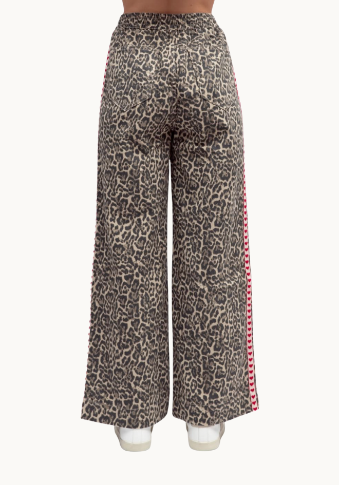 Leopard print pants with red side stripe on a white background