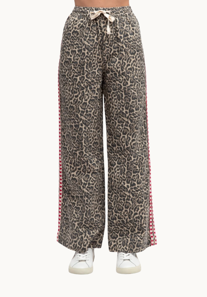 Leopard print pants with red trim on a white background