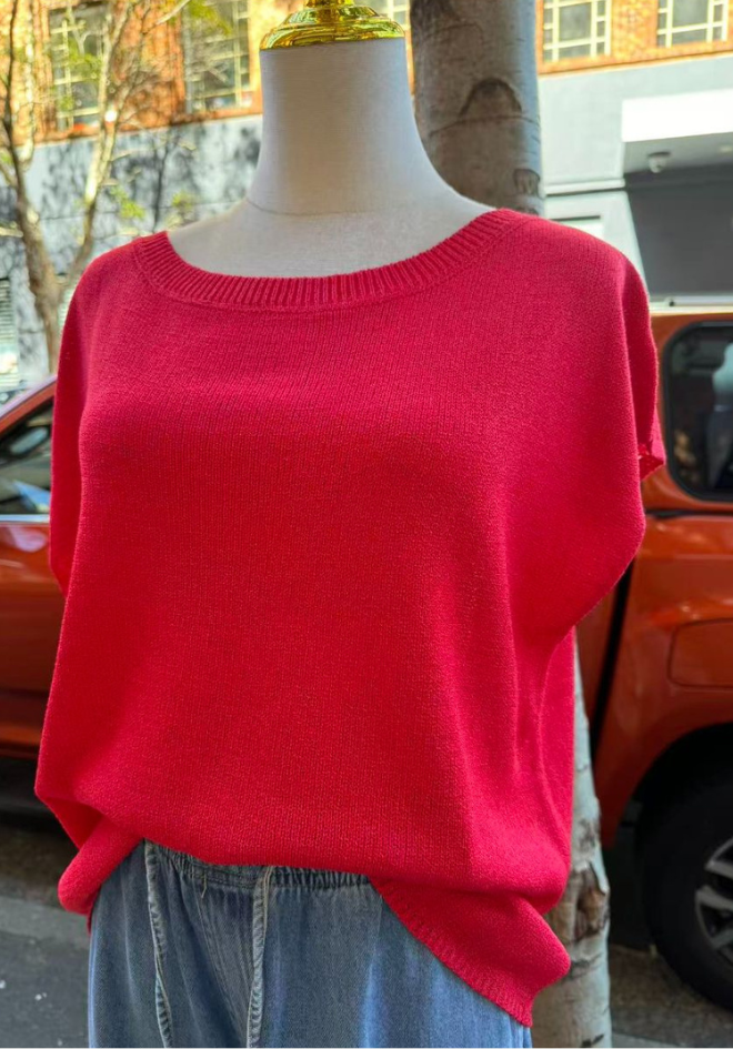 Red sweater on a mannequin with a blurred outdoor background