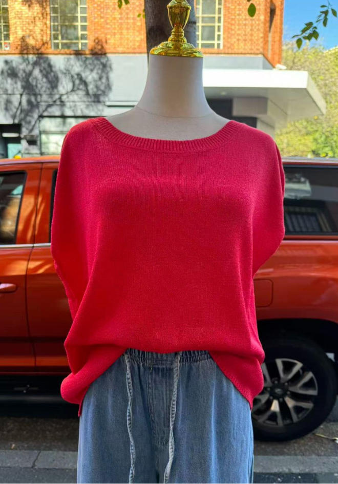 Mannequin wearing a bright pink sweater with a blurred outdoor background
