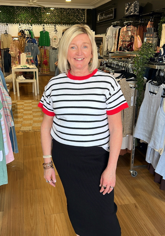 Woman in a striped shirt and black skirt standing in a clothing store.