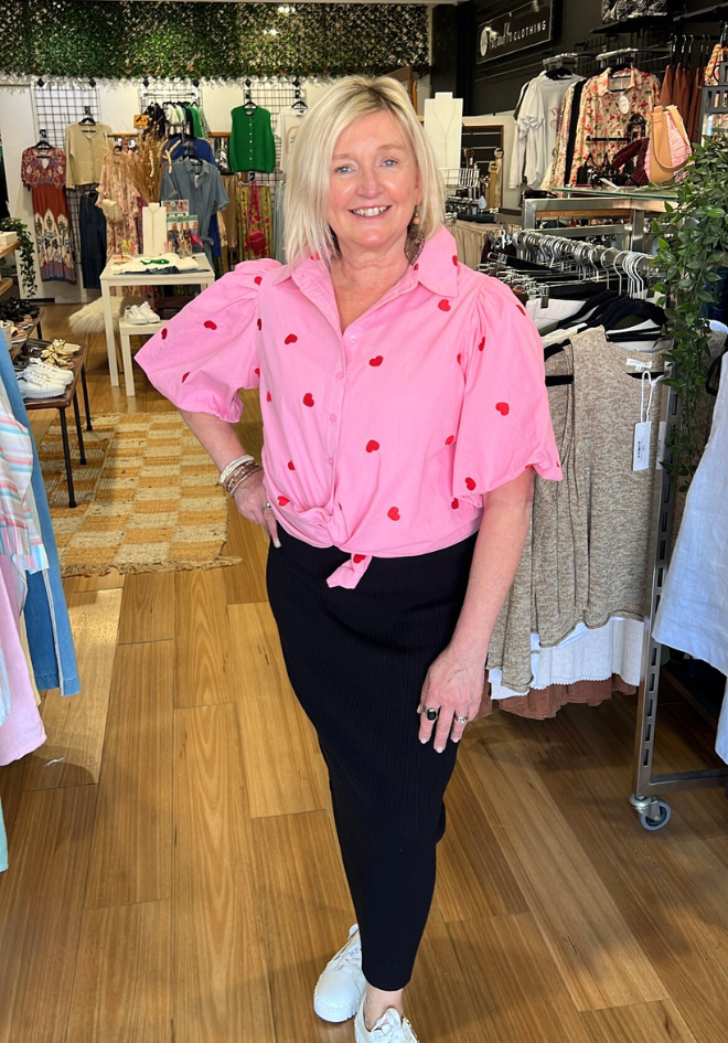 Woman wearing a pink blouse with red polka dots in a store setting