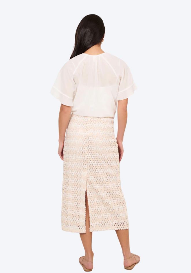 Woman wearing a white top and beige skirt on a white background