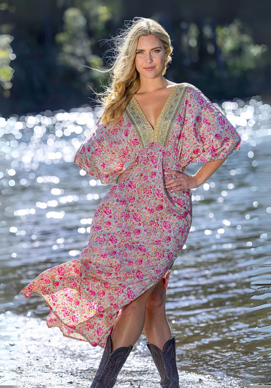 Woman in a floral dress standing by a body of water