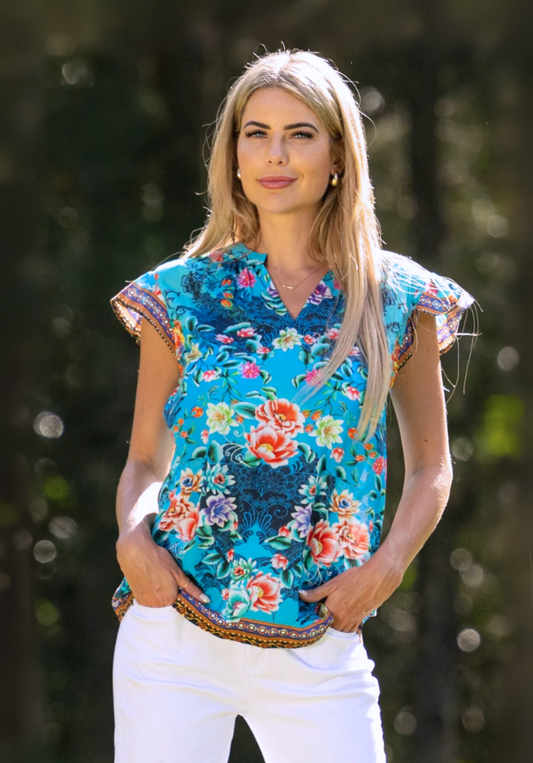 Woman wearing a colorful floral blouse with a blurred natural background