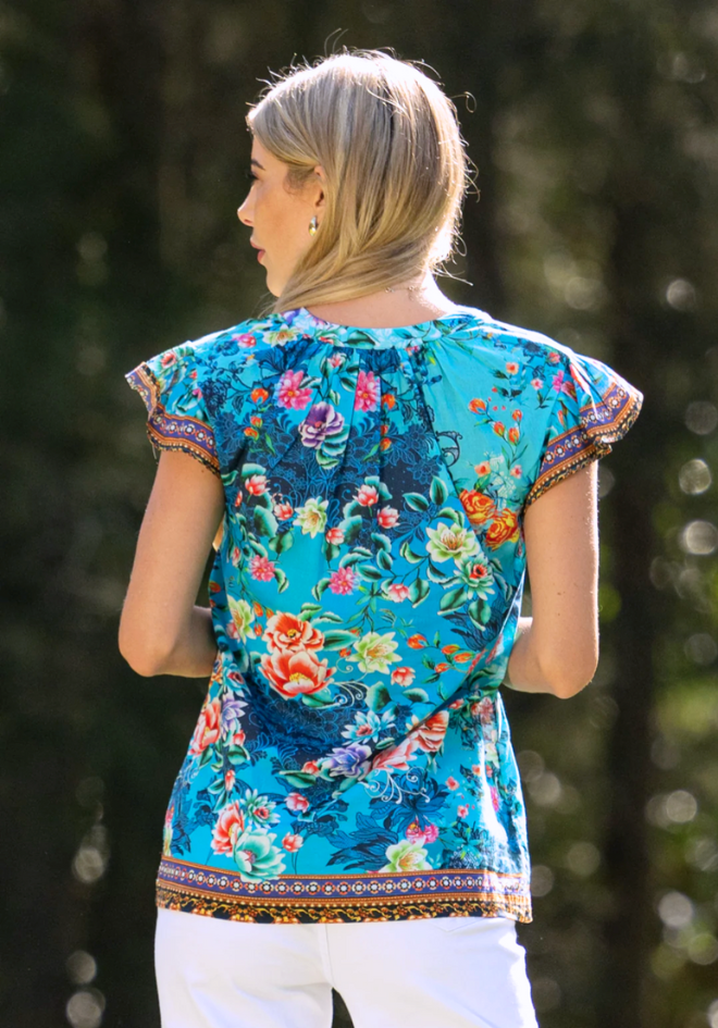 Woman wearing a colorful floral top with a blurred natural background
