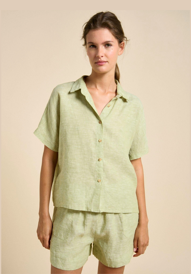 Woman wearing a light green linen shirt and shorts set on a beige background