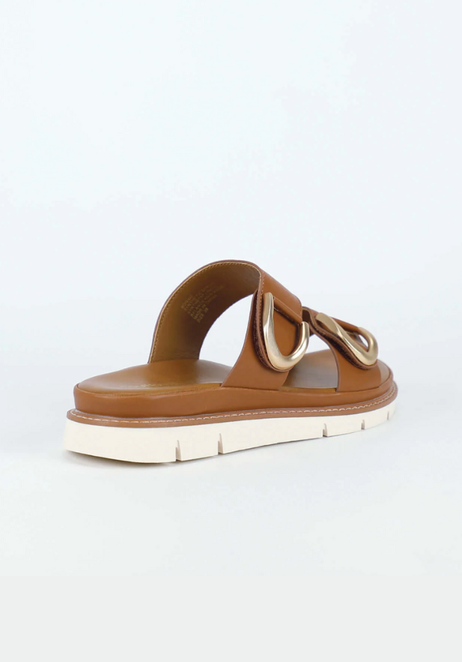 Brown sandal with a white sole on a light gray background