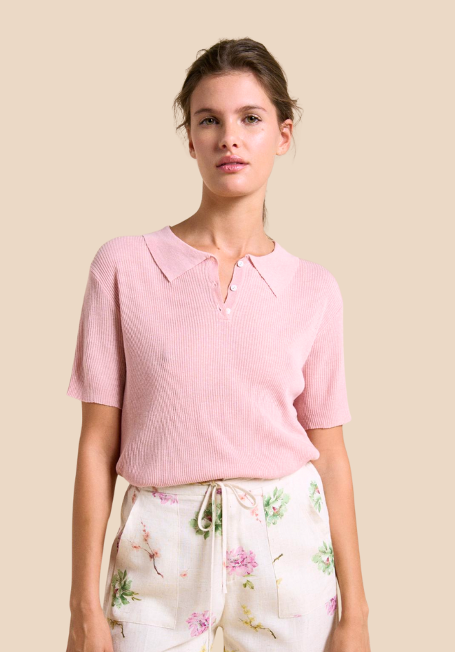 Woman wearing a pink textured top and floral pants on a beige background