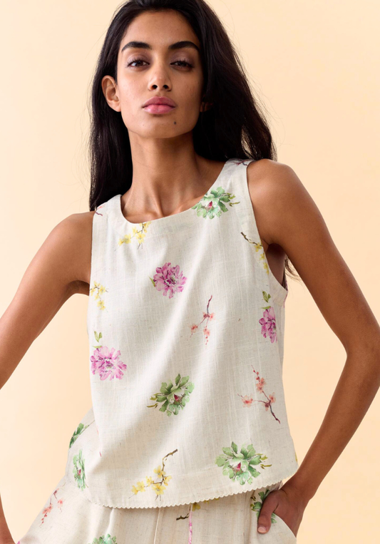 Woman wearing a white sleeveless top with floral patterns on a beige background