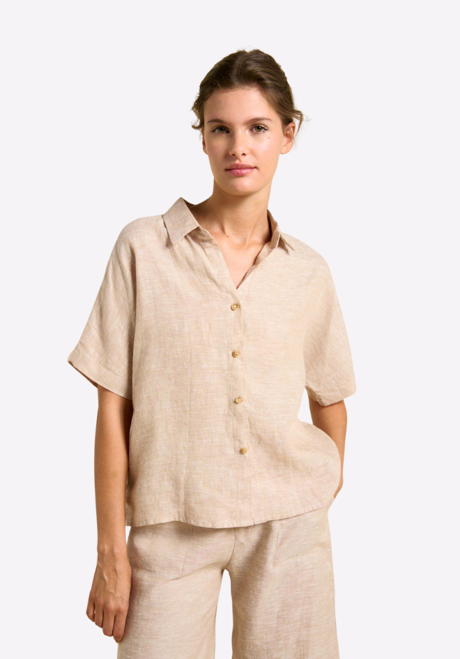 Woman wearing a beige linen shirt and pants on a white background