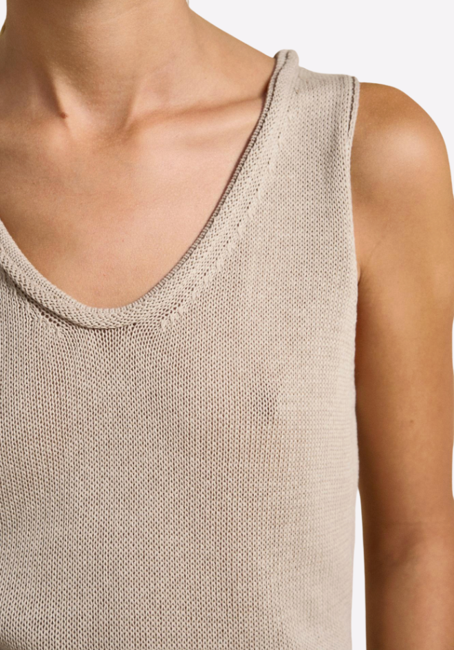 Close-up of a beige sleeveless top worn by a person on a white background