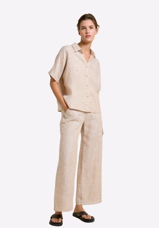 Woman wearing a beige linen shirt and pants on a white background