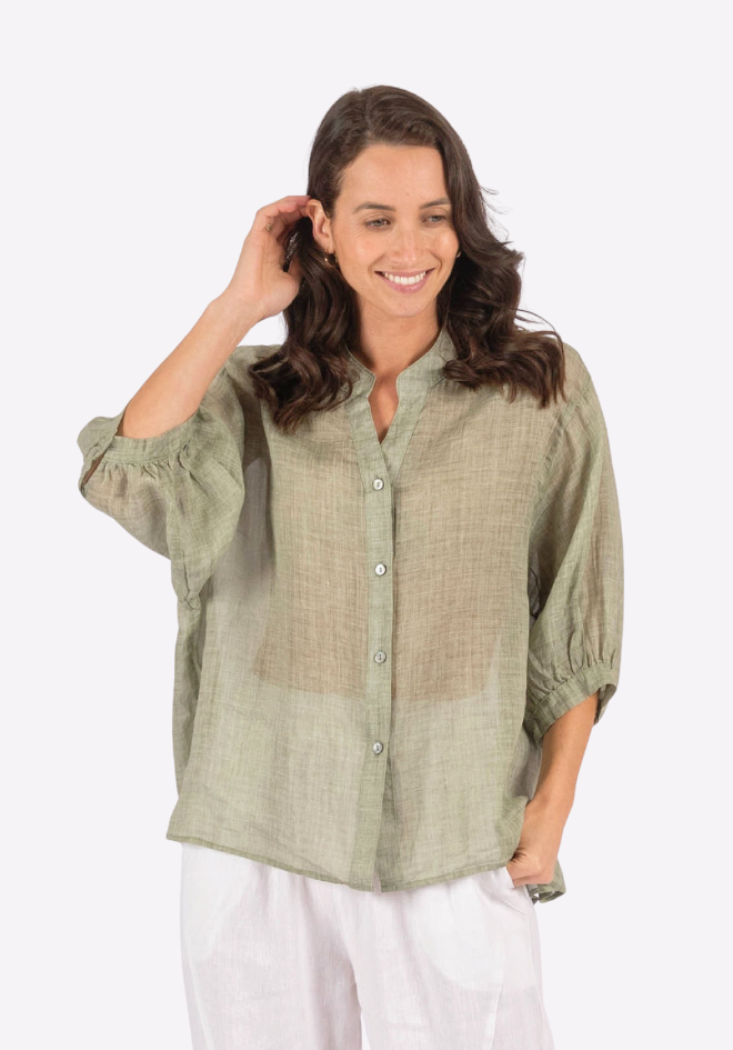 Woman wearing a green checkered shirt and white pants on a white background