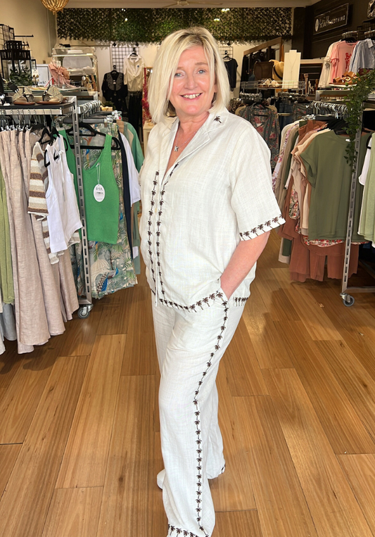 Woman in a white outfit with black trim standing in a clothing store.