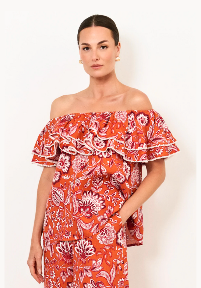 Woman wearing a red floral off-shoulder dress on a white background