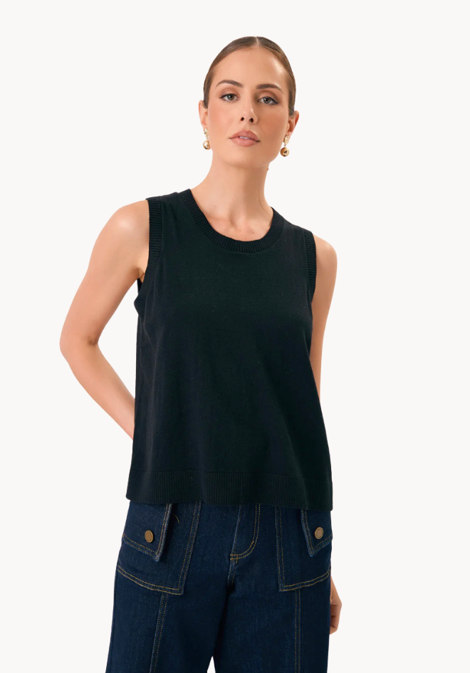 Woman wearing a black sleeveless top and blue jeans on a white background