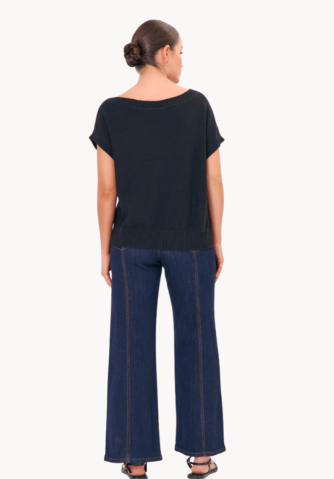 Woman wearing a black top and blue pants on a white background