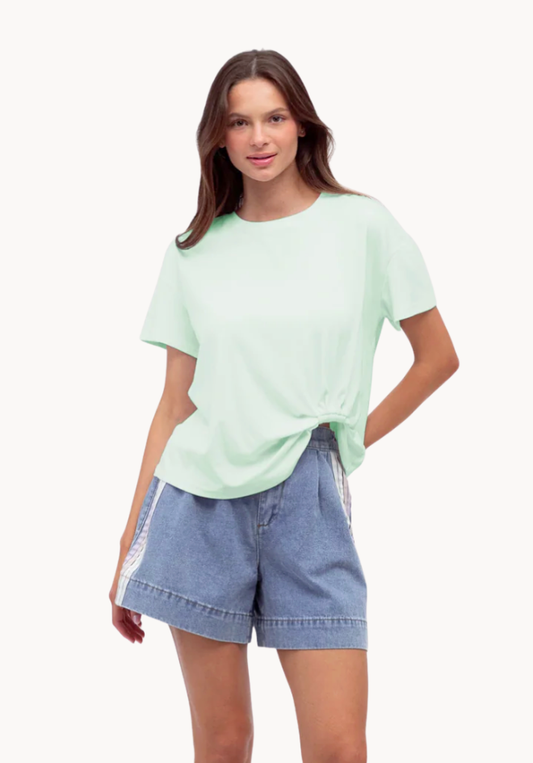Woman wearing a light green t-shirt and denim shorts on a white background