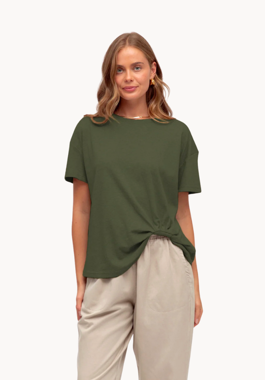 Woman wearing a green t-shirt and beige pants on a white background