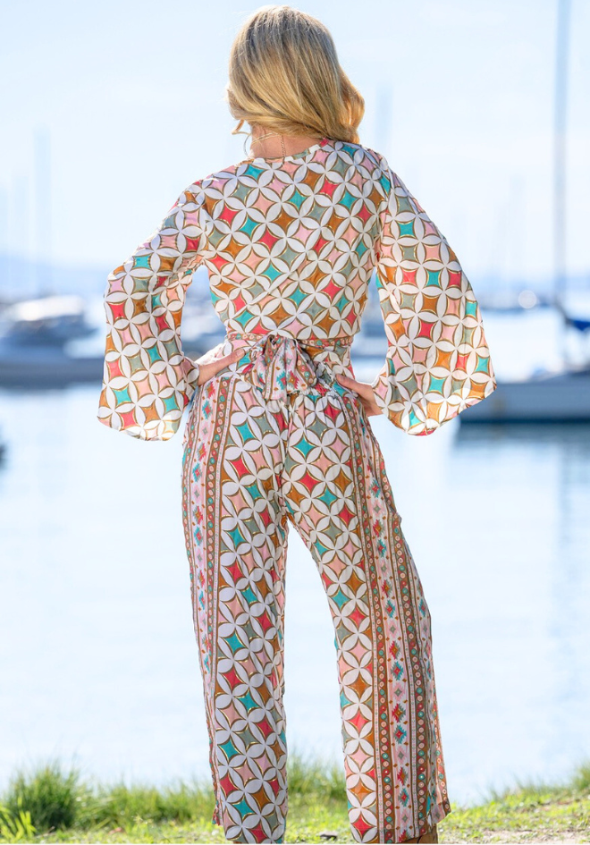 Woman wearing a colorful geometric patterned outfit by a waterfront.