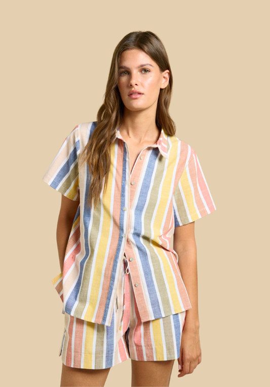 Woman wearing a colorful striped shirt and shorts set on a beige background