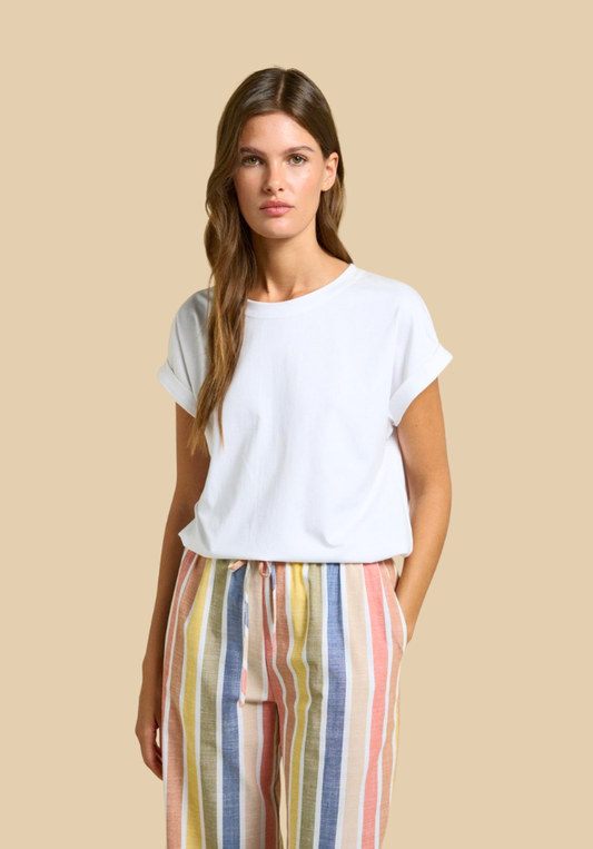 Woman wearing a white t-shirt and colorful striped pants on a beige background