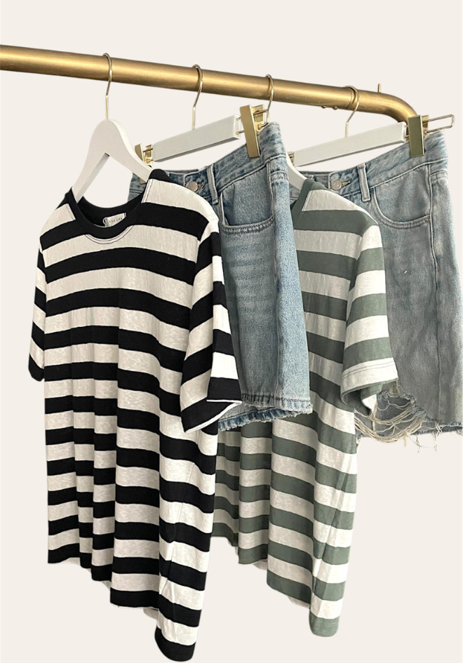 Striped shirts and denim shorts on hangers against a white background