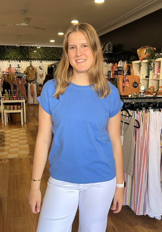Woman wearing a blue shirt and white pants standing in a store.