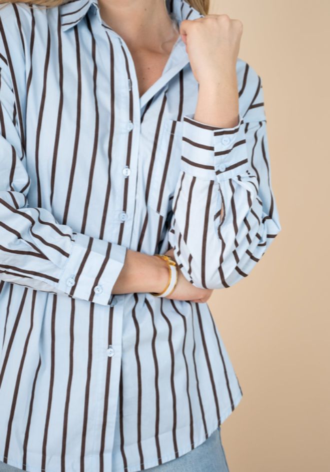 Fria The Label Billie Stripe Shirt — close-up detail of blue and chocolate stripe fabric with button placket and rolled cuffs with gold bangle, available in Australia at Kat and Ko Clothing