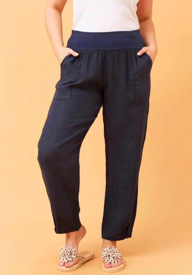 Sorrento Linen Pants in Navy by Bottega Moda — cropped front view of navy relaxed linen pants with wide elastic waistband and side pockets, styled with white top and embellished flat sandals on orange background, available in Australia at Kat and Ko Clothing