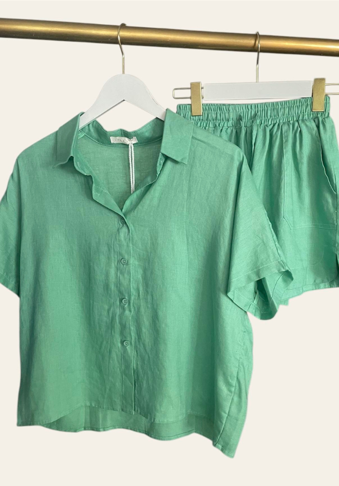 Aqua colored linen shorts with an elastic waistband and adjustable tie, featuring pockets.