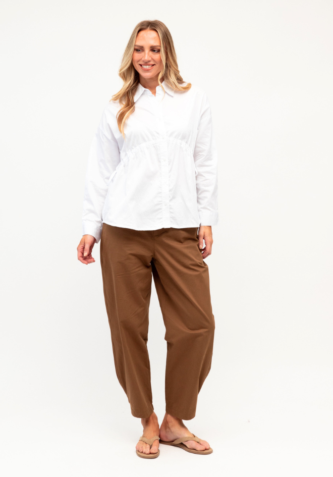 Label of Love Kori Shirt in White — full-length front view of white cotton button-up shirt with side tie waist, styled with wide-leg tan trousers and sandals, shop in Australia at Kat and Ko Clothing